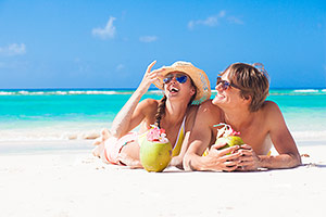 Couple sipping drinks on Caribbean beach